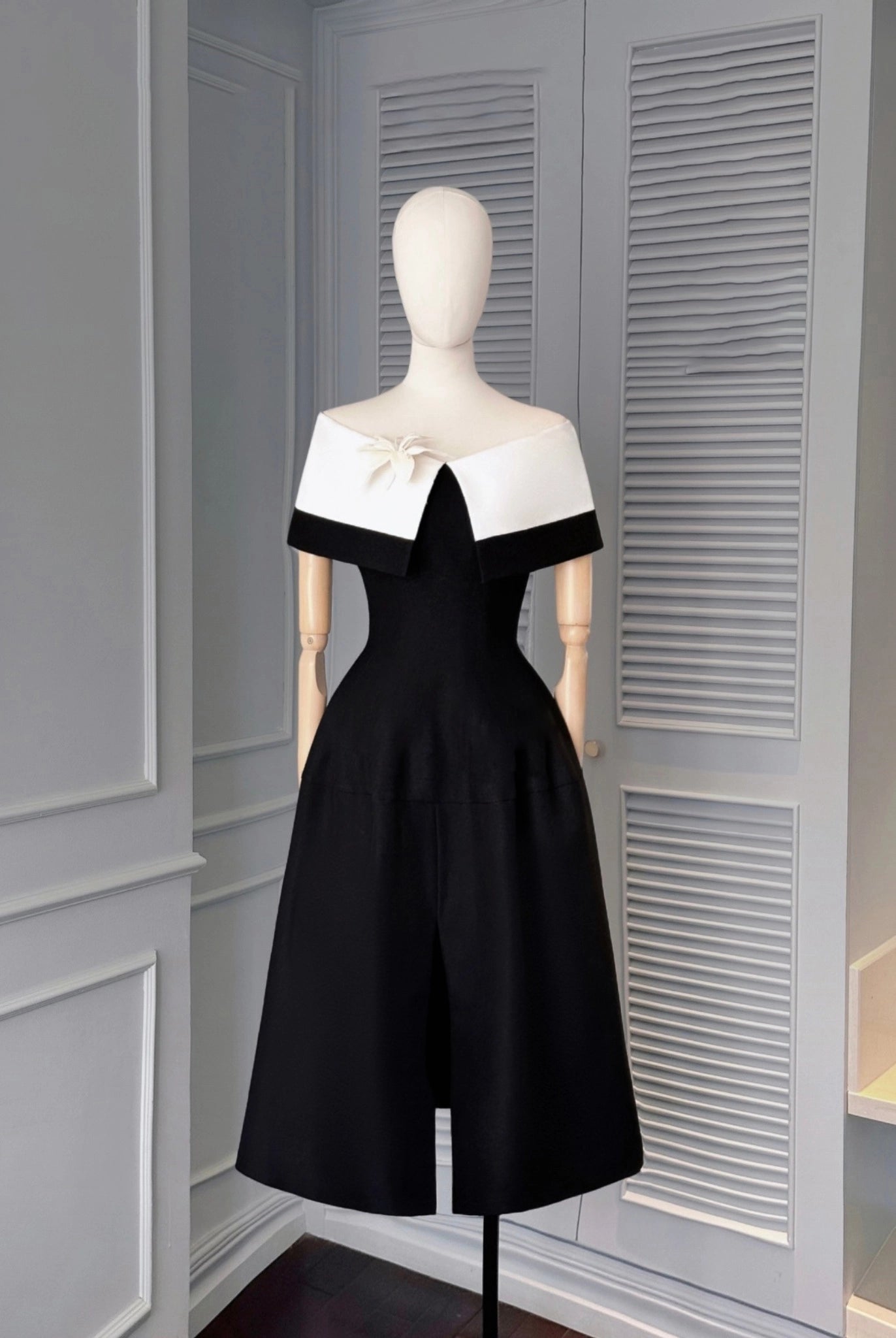 Black and white dress on a mannequin against a gray wall.