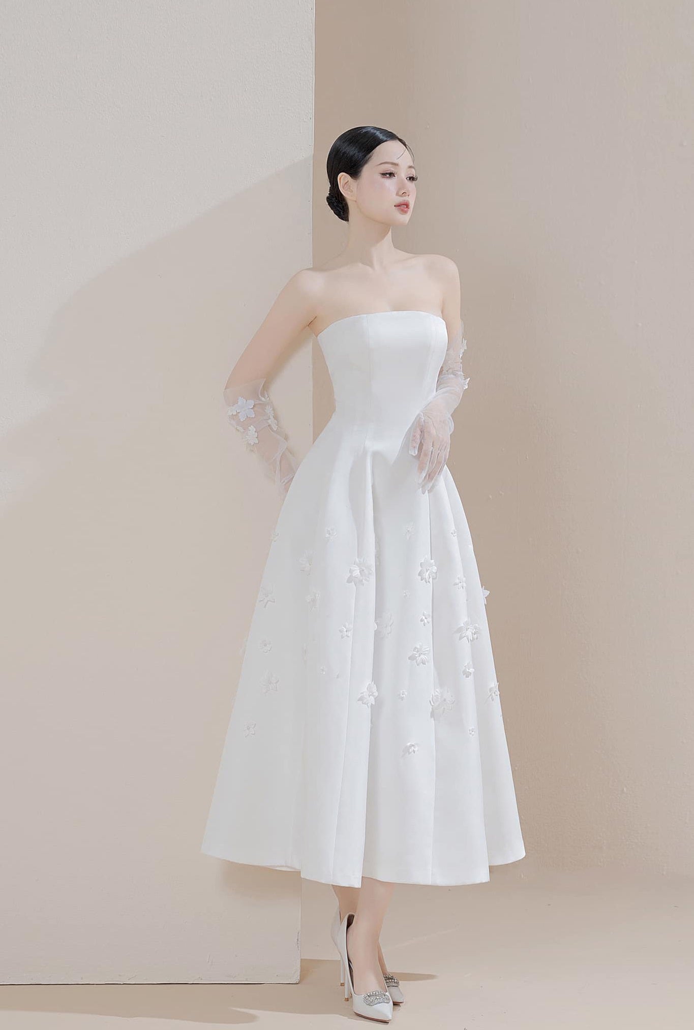 Woman wearing a white strapless dress with a plain background