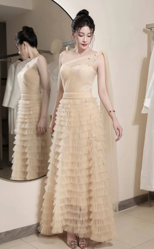 Woman wearing a beige ruffled dress in front of a mirror.