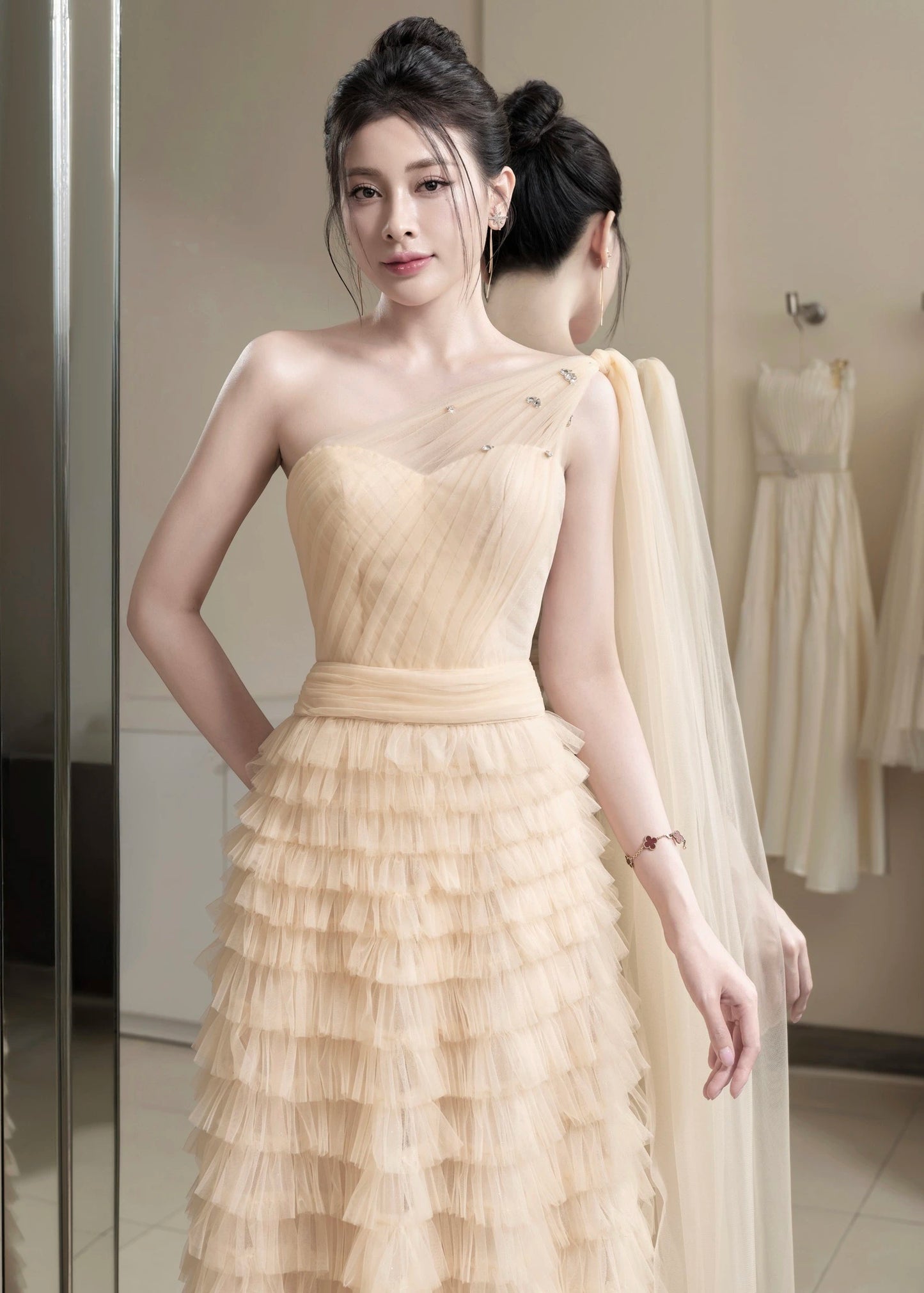 Woman in a beige evening gown standing in front of a mirror.