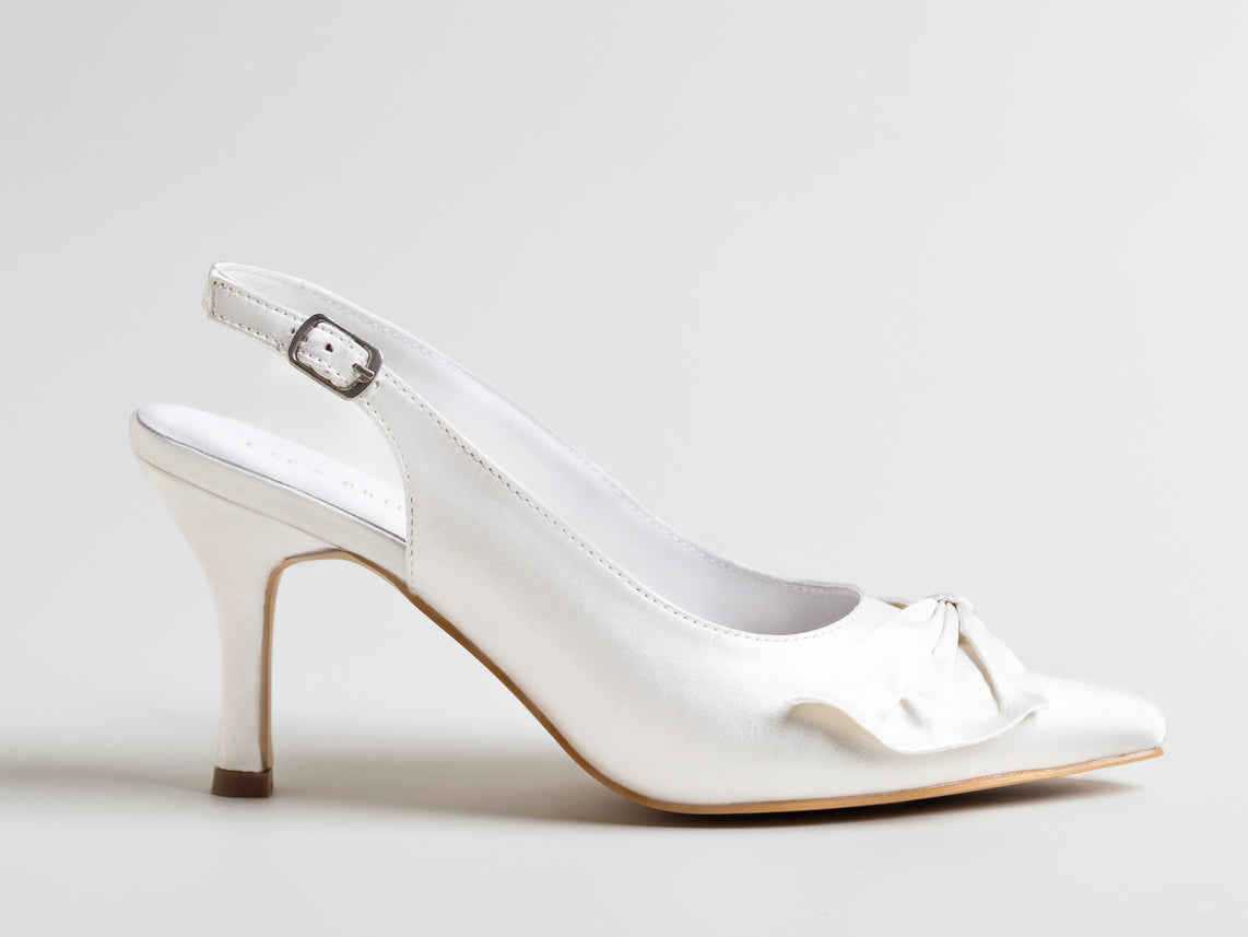 White high-heeled shoe with a bow on a light gray background