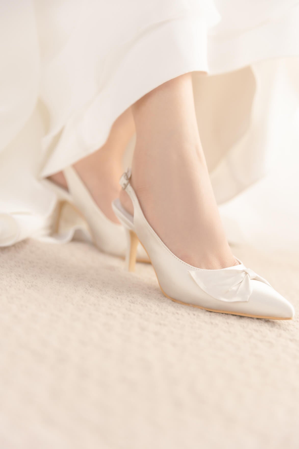 White satin wedding shoes on a soft beige background