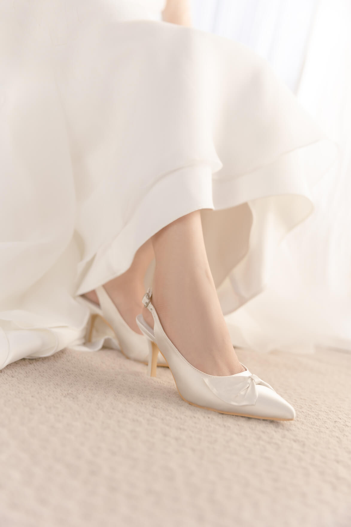 White wedding shoes worn with a white dress on a light background