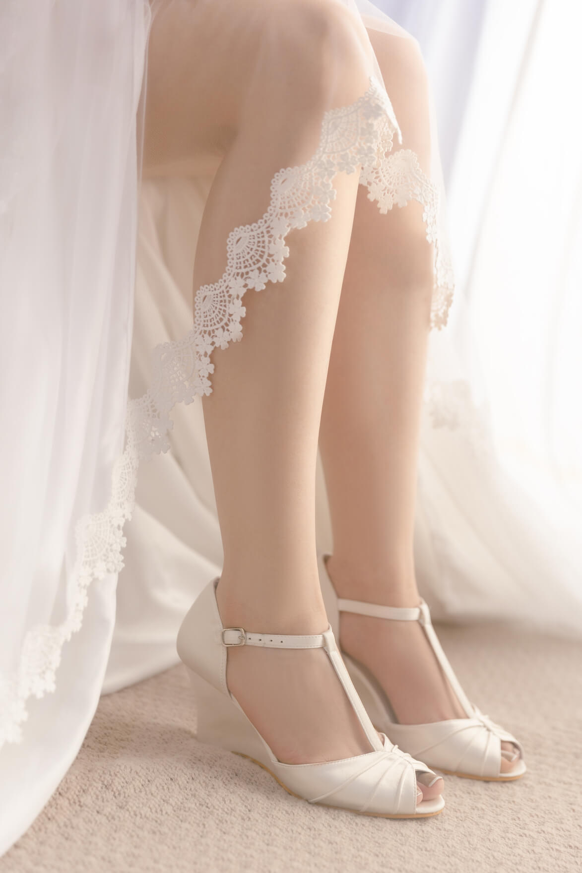 White lace-trimmed stockings and white shoes on a neutral background