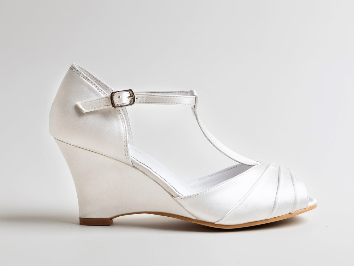 White wedge shoe with a strap on a light gray background