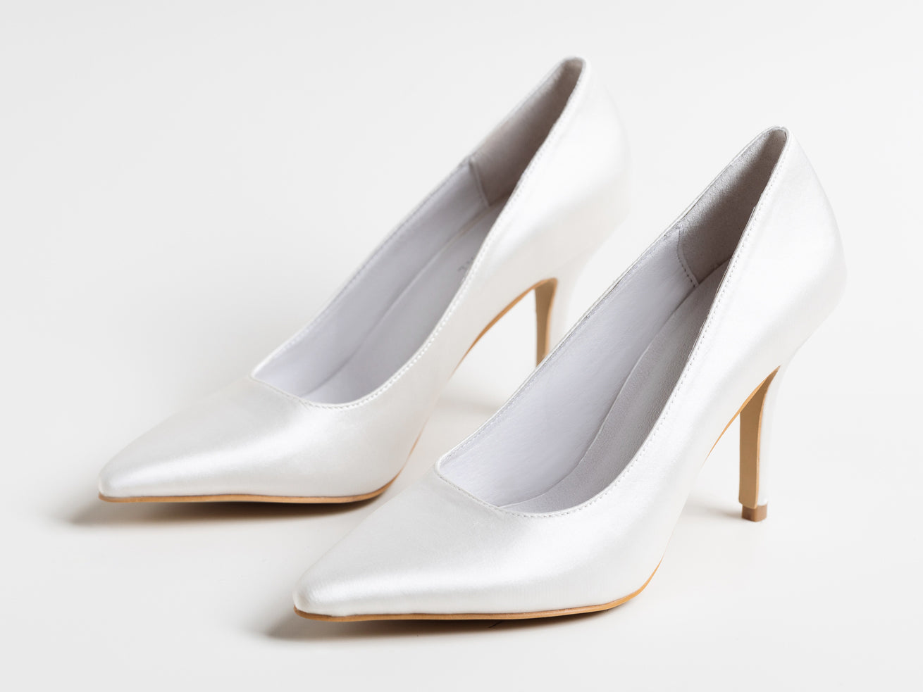 Pair of white high-heeled shoes on a light gray background
