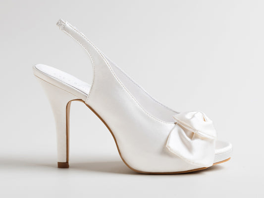 White high-heeled shoe with a bow on a light gray background