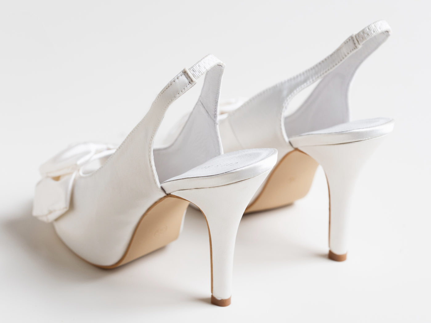 Pair of white high-heeled shoes on a light background