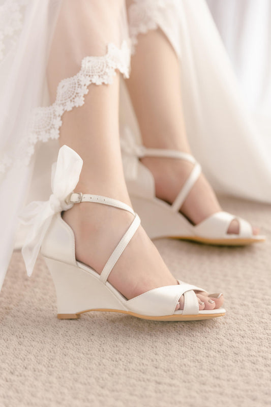 White wedding shoes with bows worn by a bride.
