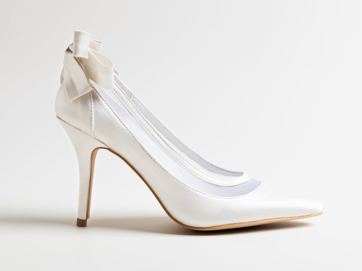 White high-heeled shoe with a bow on a light gray background