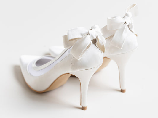 White high-heeled shoes with bows on a light background