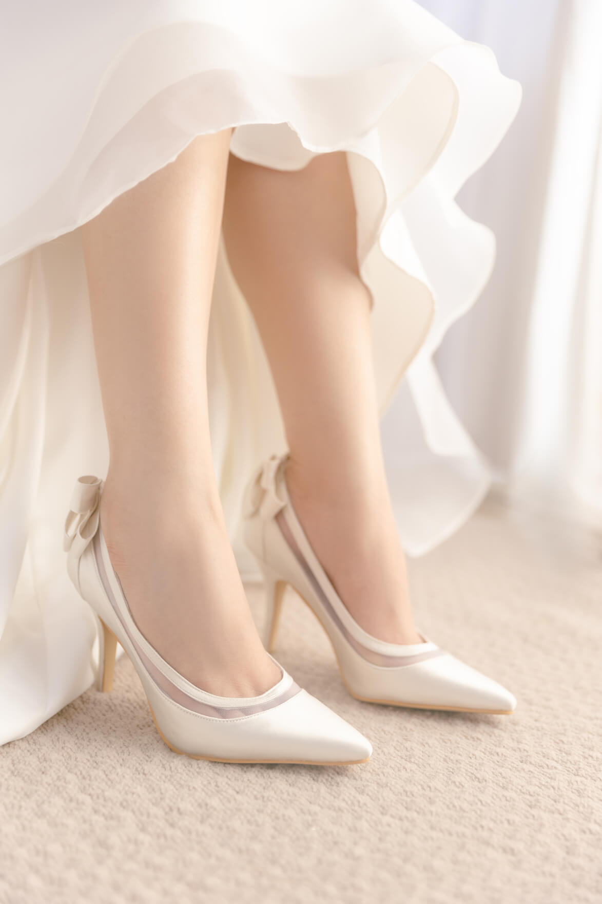 White satin shoes with a bow on a light background