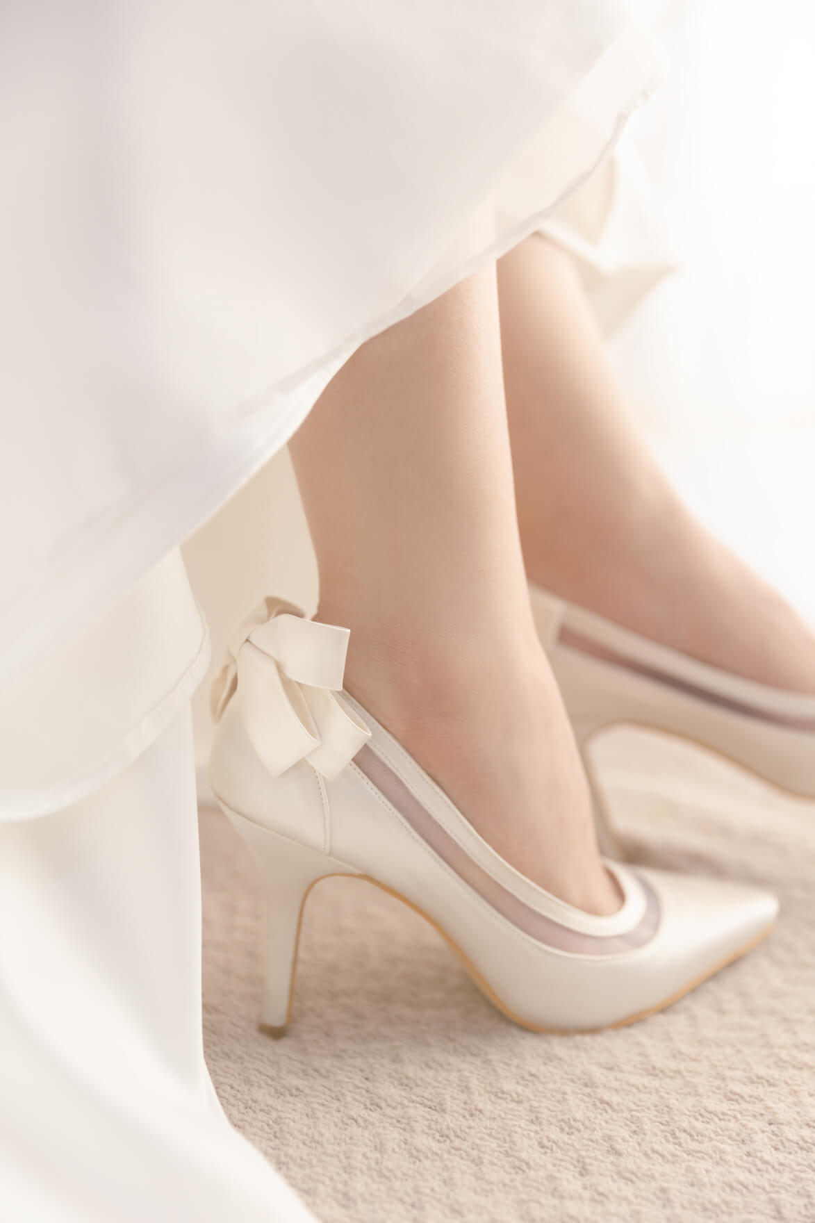 White high-heeled shoes with a bow on a light background