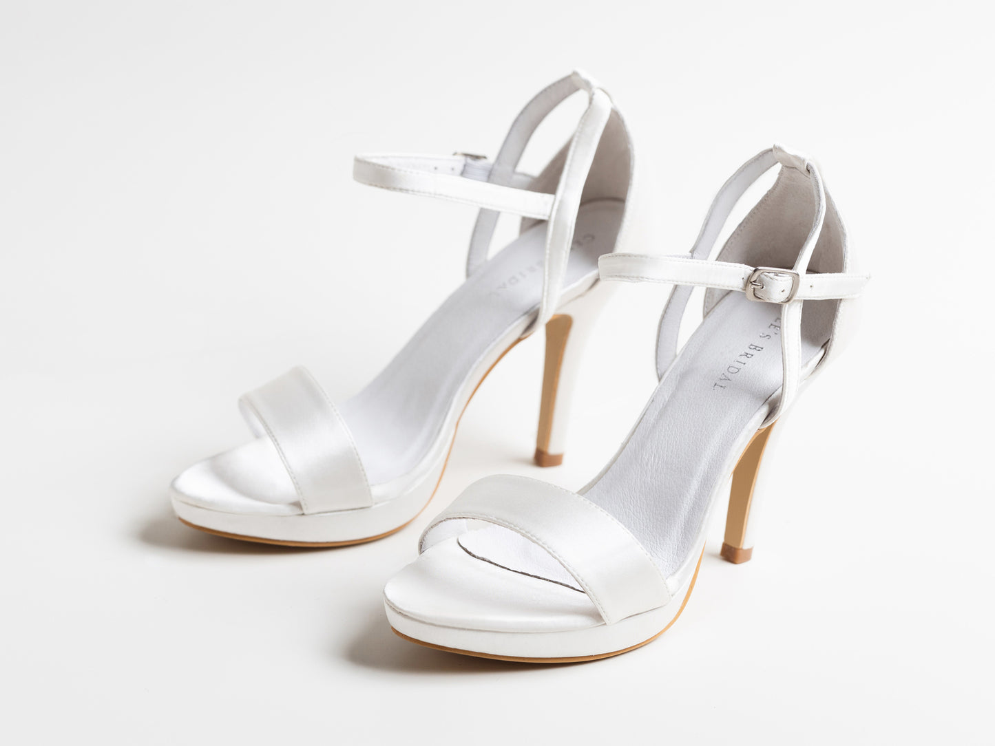 Pair of white high-heeled sandals on a light gray background