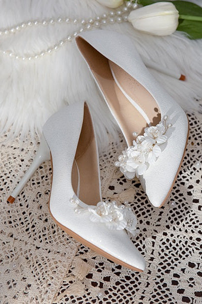 Side view of Elegant White Metallic Leather Wedding Heels with floral embellishments, displayed with a white flower and candle.