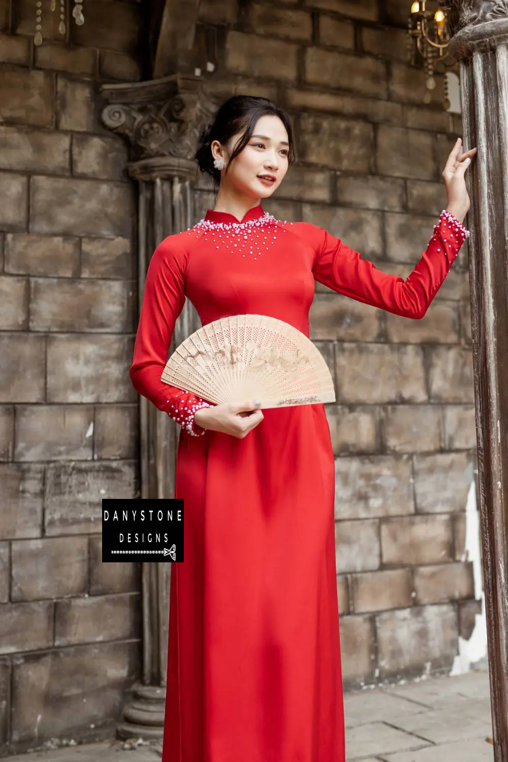 Woman in a red silk Áo Dài, showcasing the pearl-embellished neckline and cuffs.