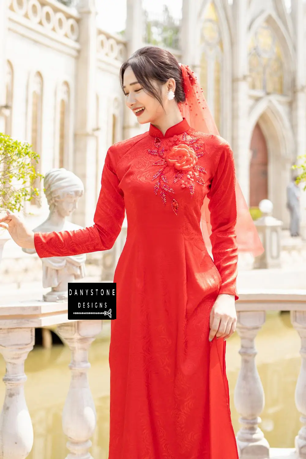 Close-up of a red brocade Áo Dài with a large crimson flower and beaded leaves on the chest.
