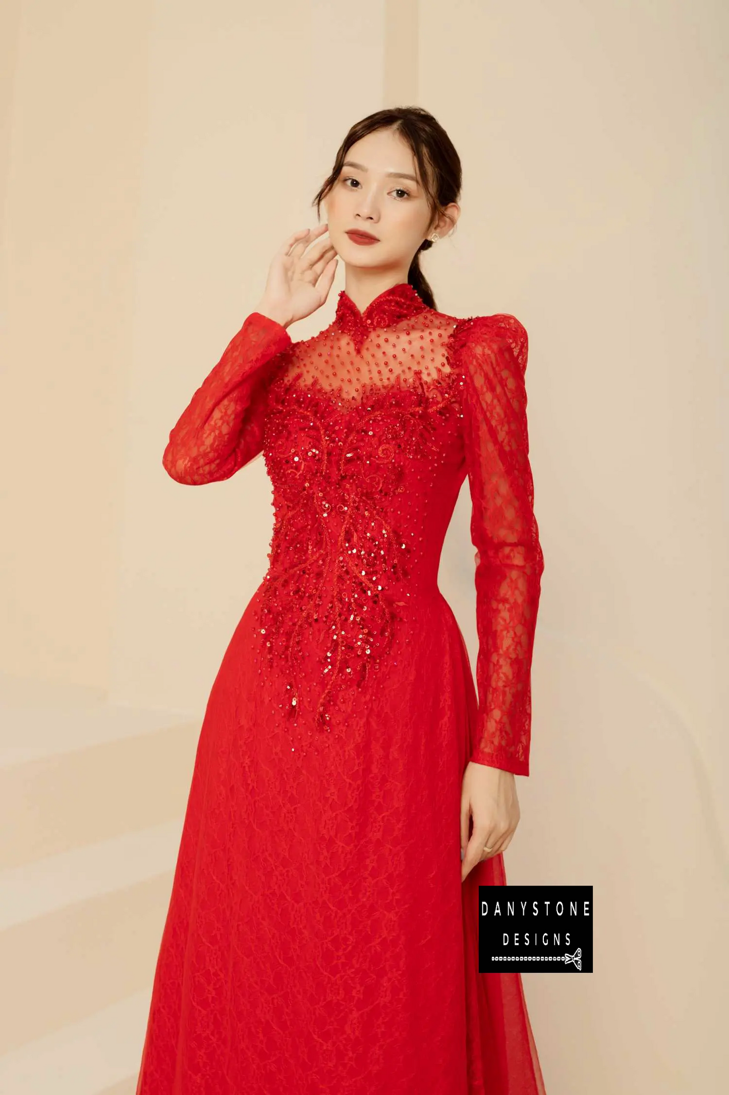 Woman in a red lace Áo Dài with a long standing collar and intricate beaded details.