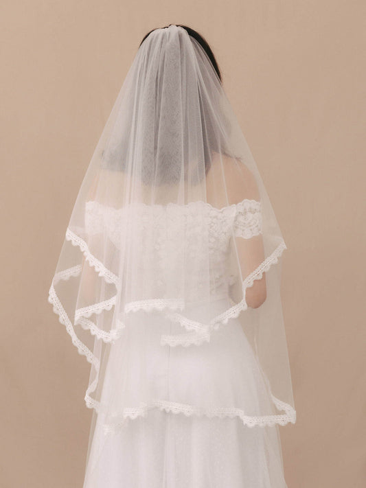 Bride wearing a white wedding dress with a veil against a beige background