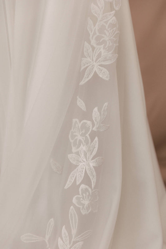 Close-up of a sheer fabric with floral embroidery on a beige background