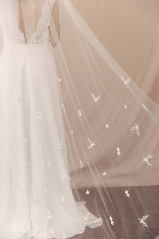 White wedding dress with floral embellishments on a plain background