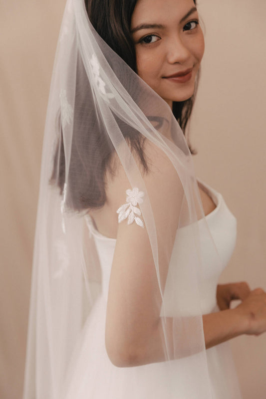 Woman wearing a white wedding dress with a veil against a beige background