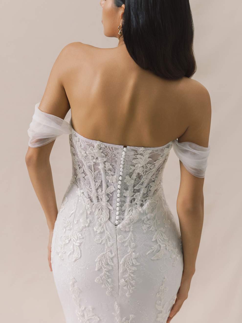 White lace wedding dress with sheer sleeves on a neutral background