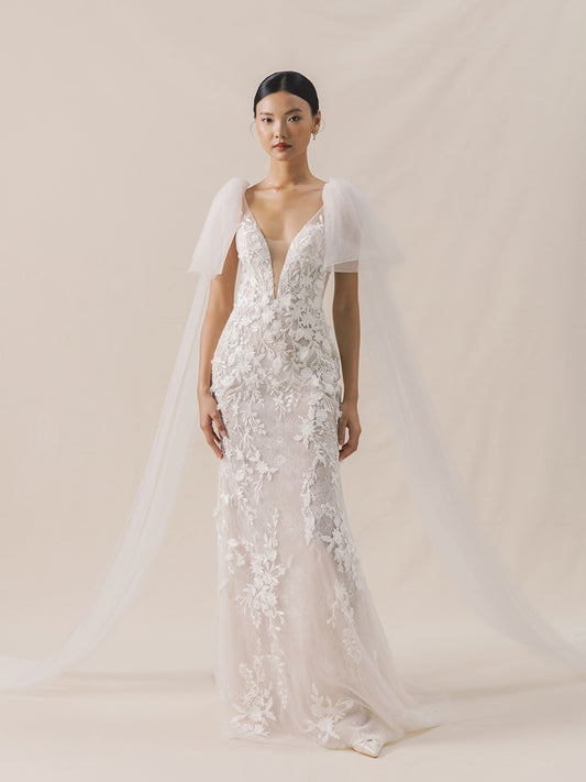 Woman wearing a white lace wedding dress with a plain background