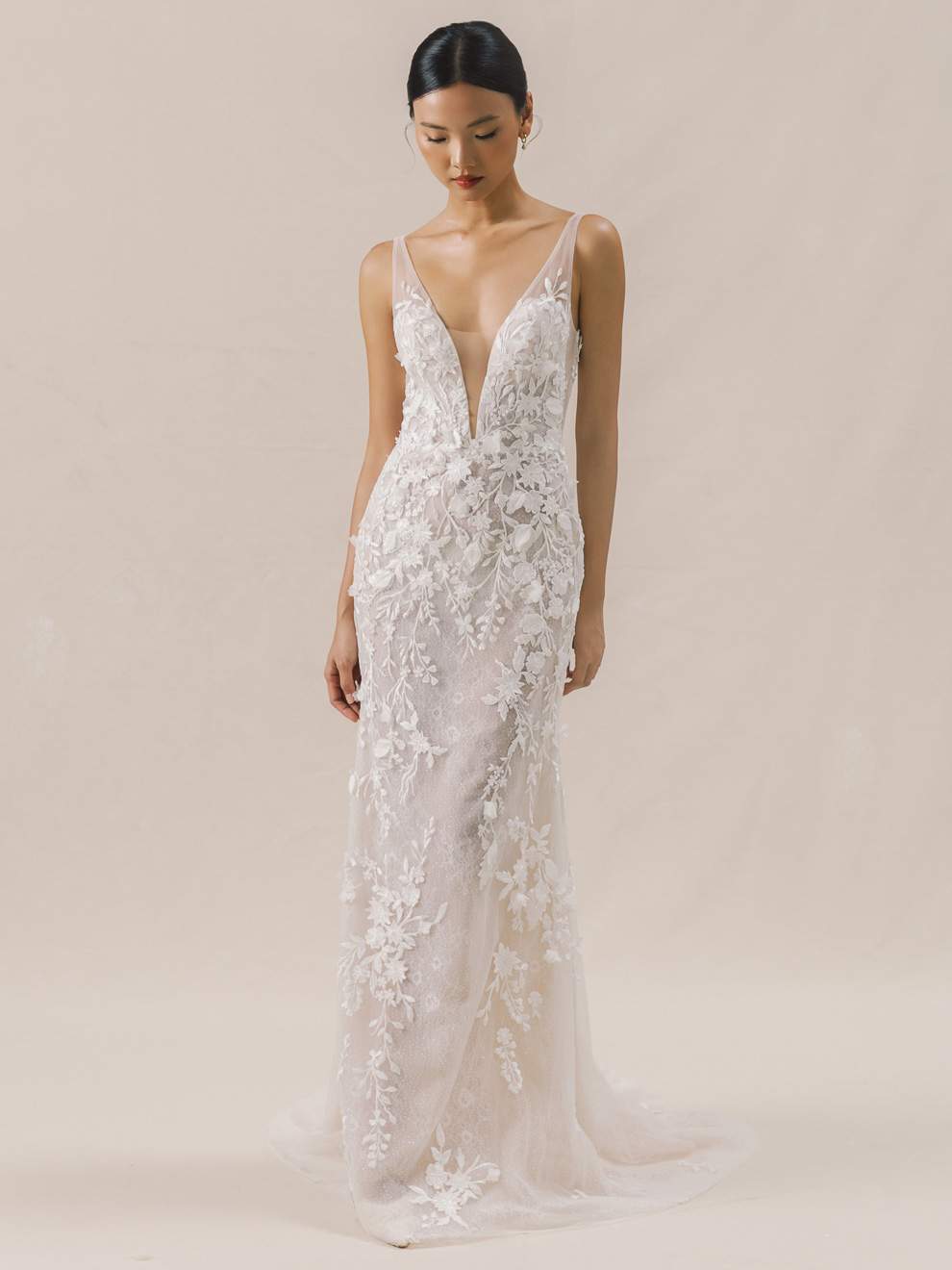 Woman wearing a white lace wedding dress against a beige background