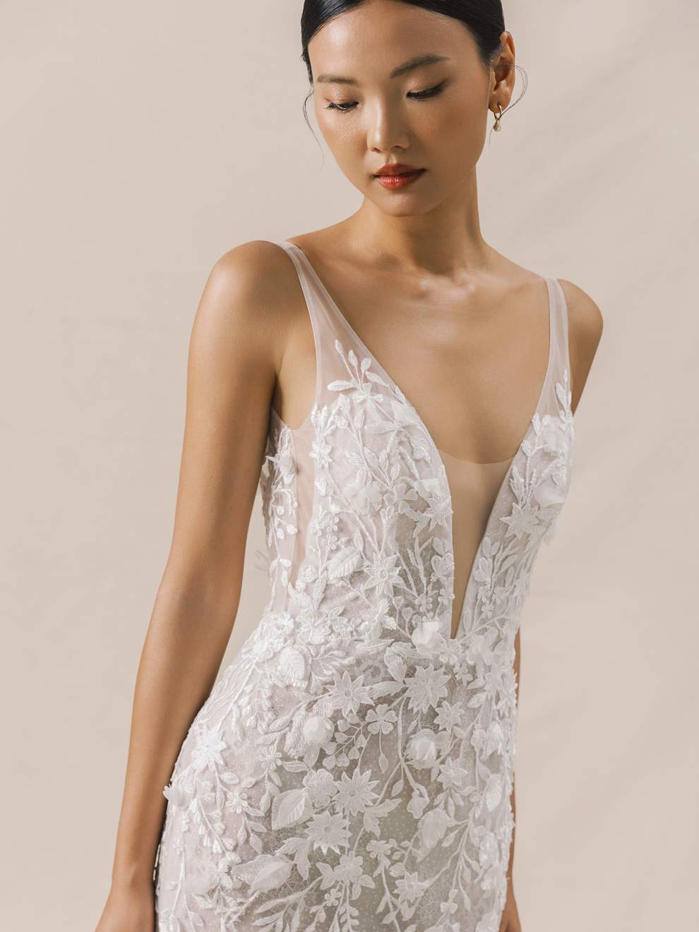 Woman wearing a white lace dress with a deep neckline on a beige background
