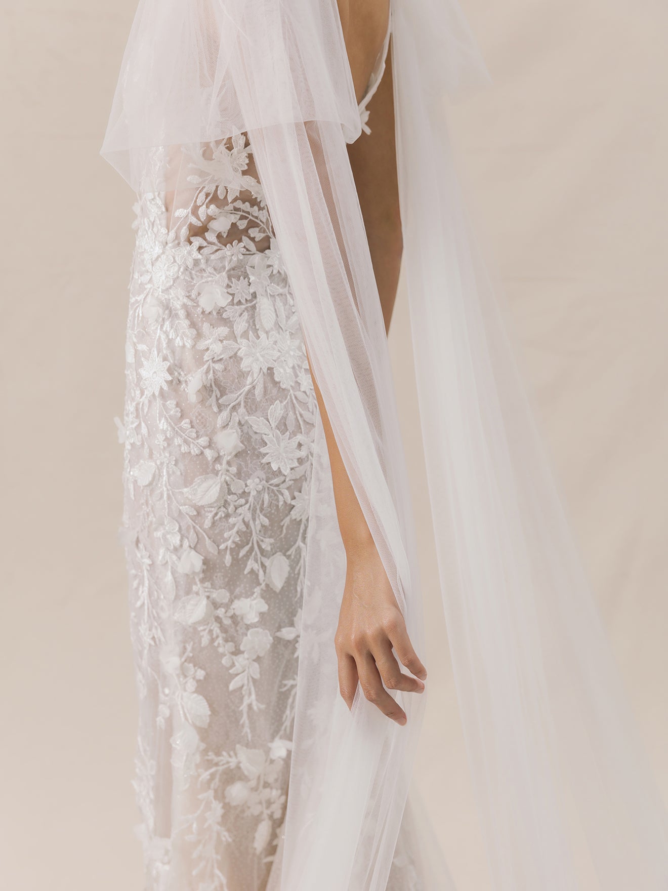 White lace wedding dress with a sheer overlay on a neutral background