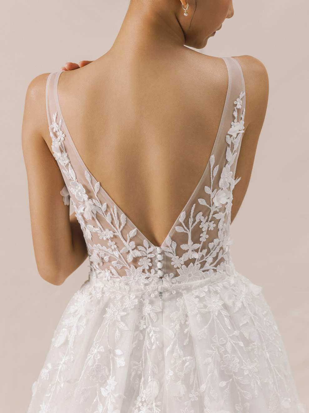 White lace wedding dress with a deep back on a neutral background