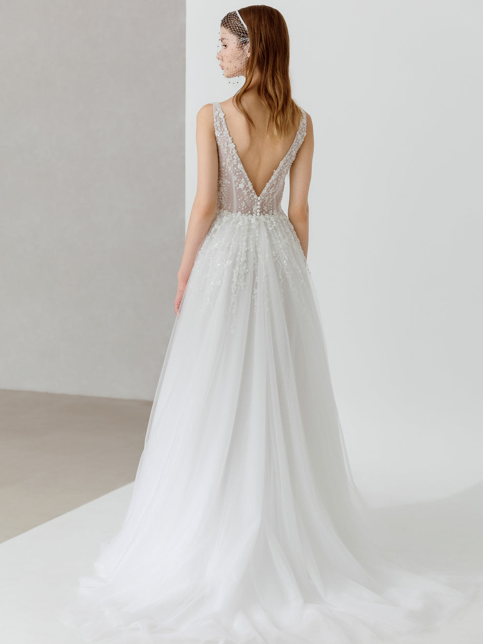 White wedding dress with a deep neckline and sheer bodice on a plain background