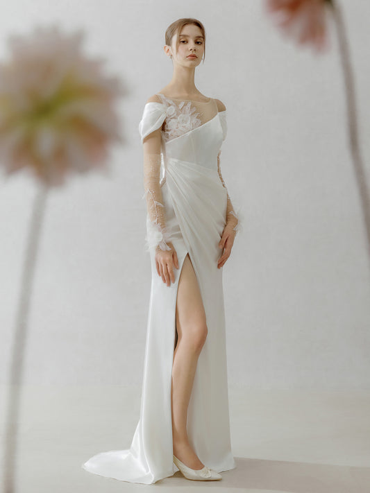Woman wearing a white wedding dress with a high slit on a plain background