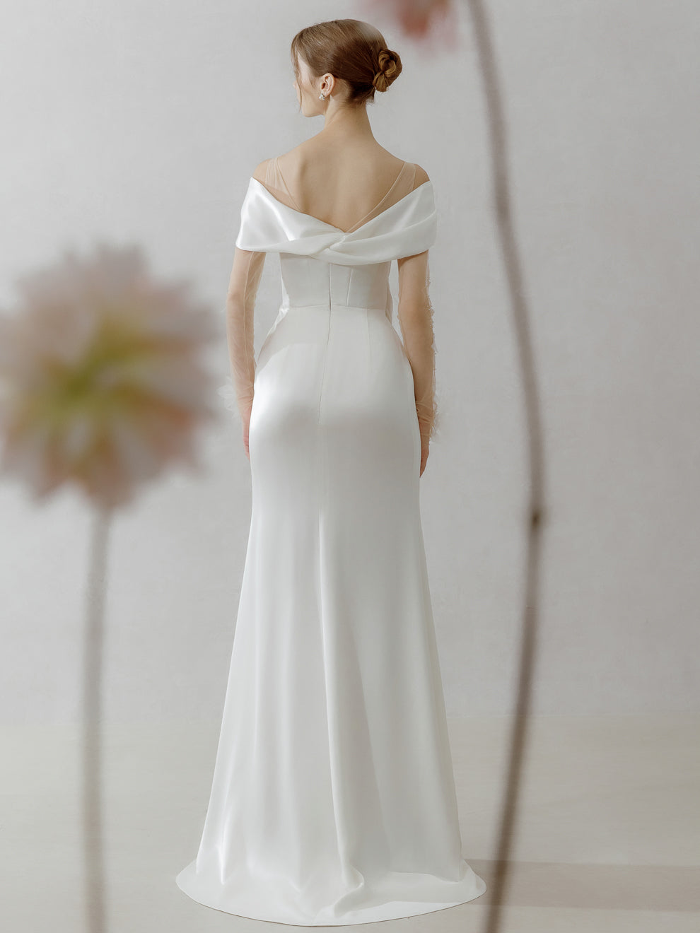 Woman wearing a white off-shoulder gown with a plain background