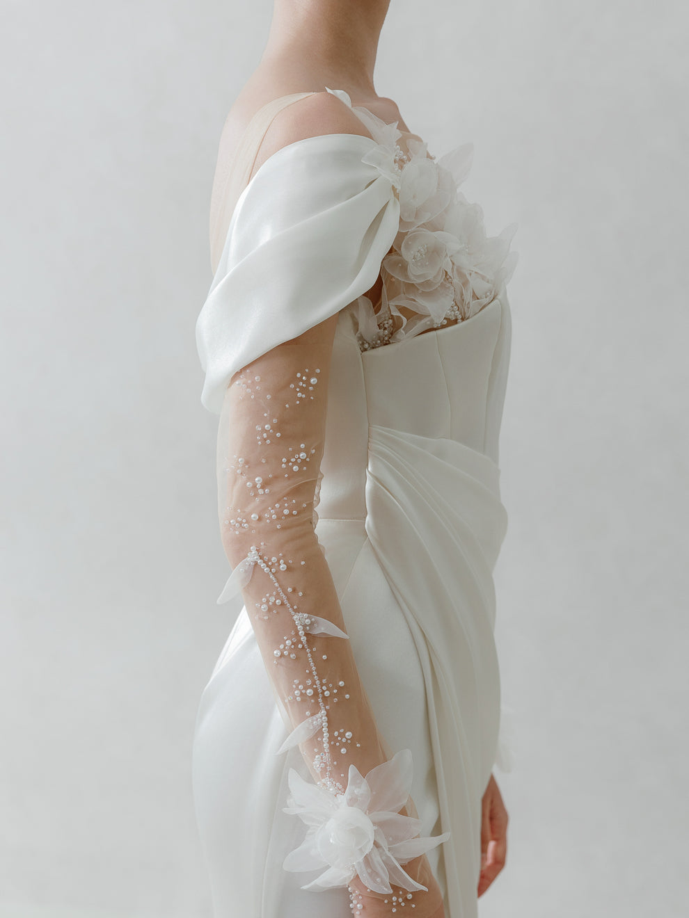 Close-up of a white wedding dress with lace details on a plain background