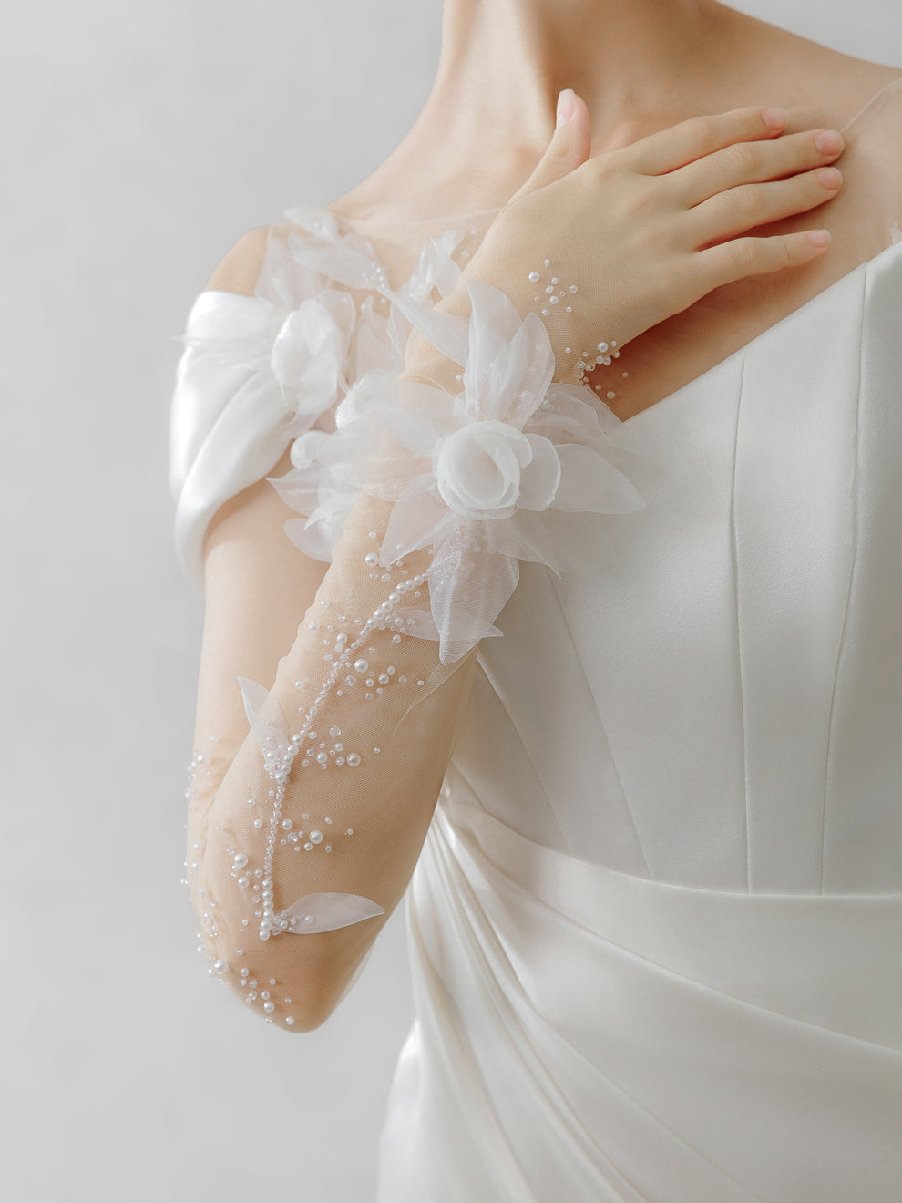 White lace gloves with floral details on a plain background