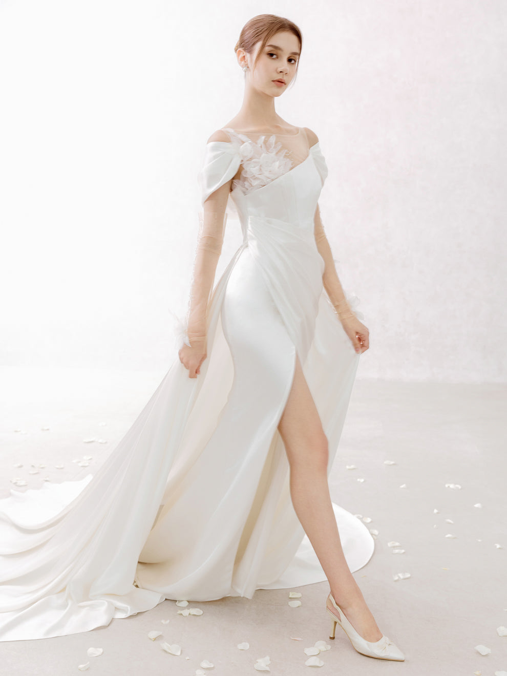 Woman wearing a white off-shoulder gown with a high slit on a white background