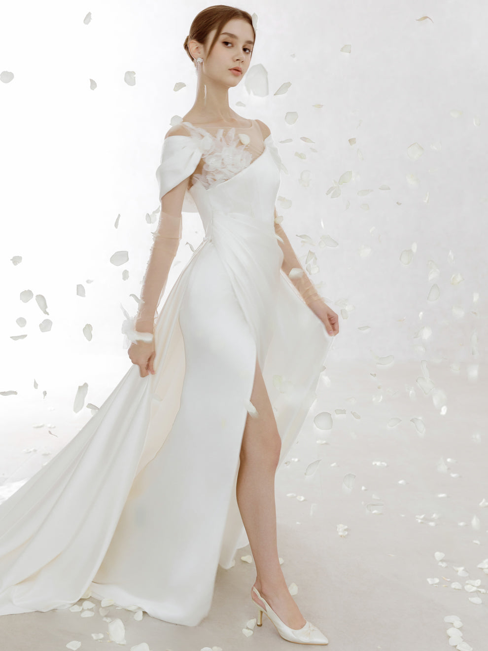 Woman in a white off-shoulder gown with floral details on a white background