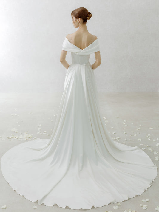 White wedding dress with a long train on a plain background