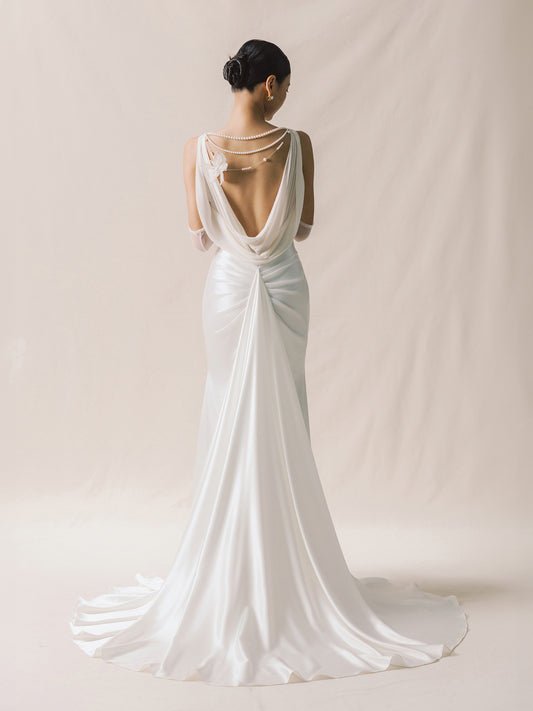 White wedding dress with open back on a plain background