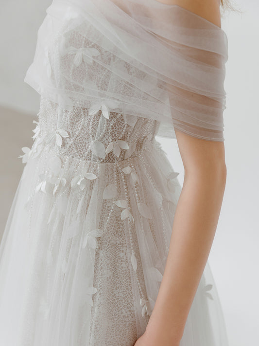 Close-up of a light gray wedding dress with floral details on a plain background