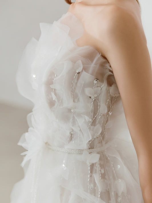 Close-up of a strapless wedding dress with floral details and a belt.