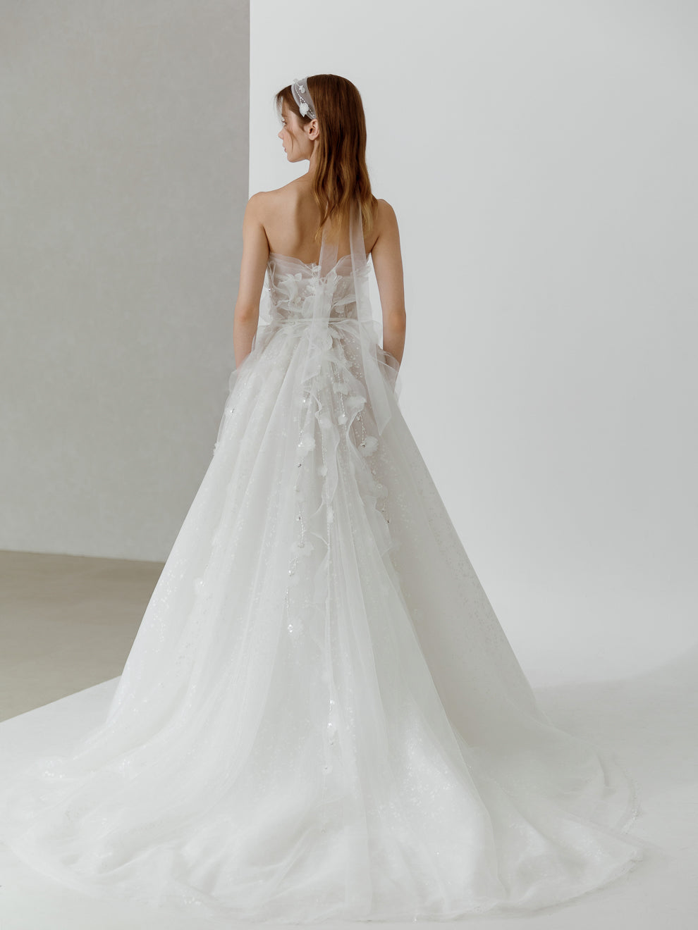 Woman wearing a white wedding dress with a long train in a minimalistic setting