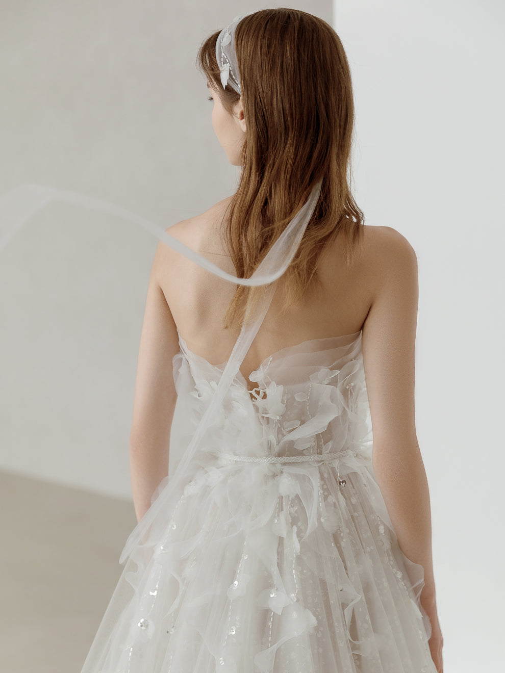 Woman wearing a white floral dress with a sheer overlay against a plain background