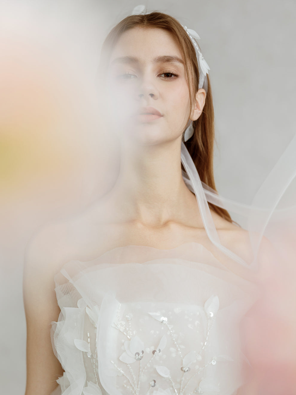 Woman wearing a white wedding dress with a veil against a soft, blurred background