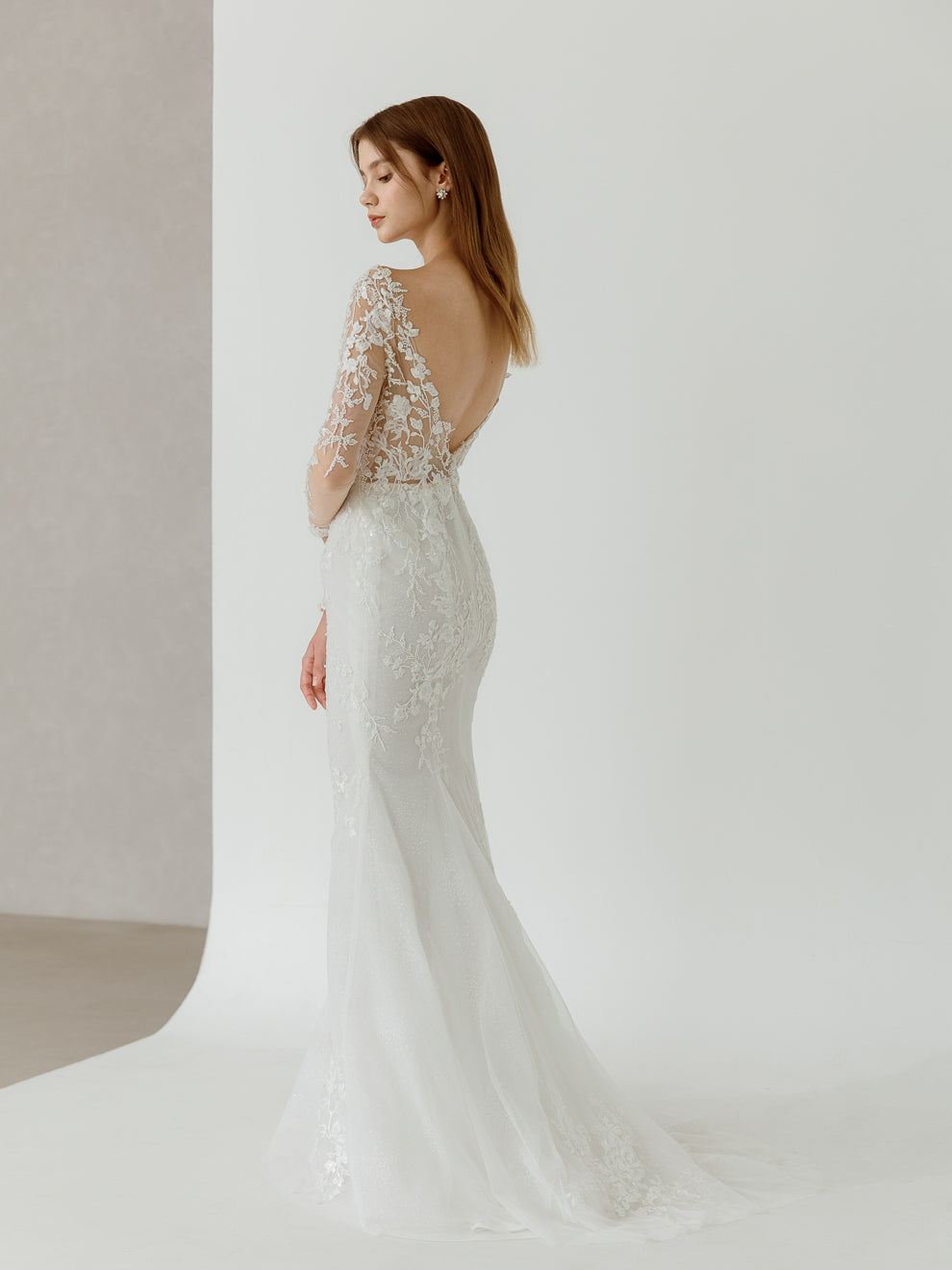 Woman wearing a white lace wedding dress with a plain background