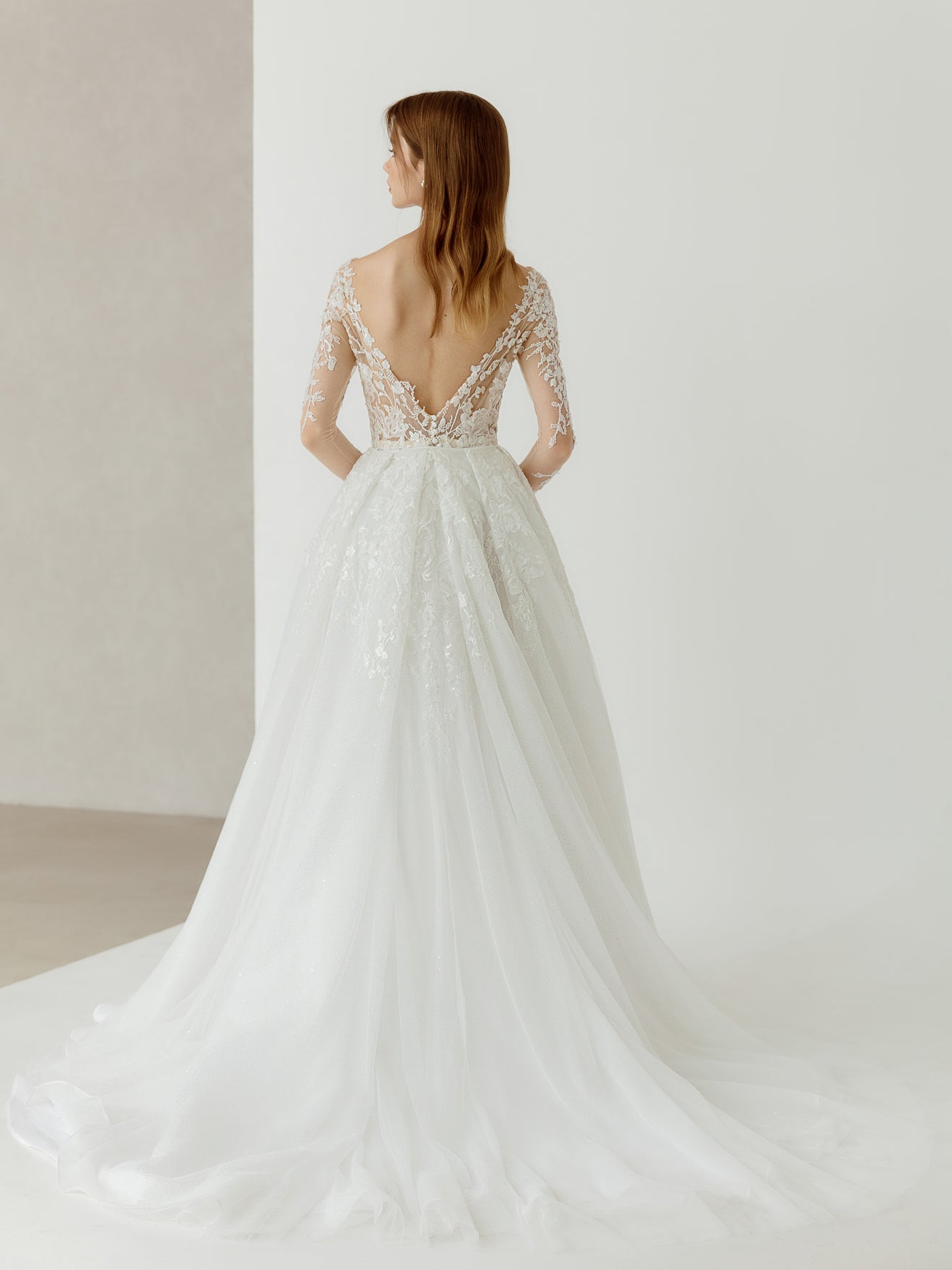Woman wearing a white wedding dress with lace detailing in a minimalistic setting