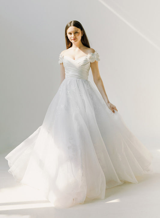 Woman wearing a white wedding dress against a plain background