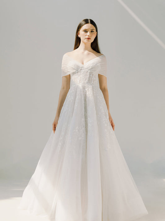 Woman wearing a white wedding dress against a plain background